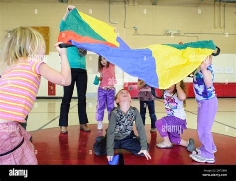 Pre School Children Playing With Rainbow Parachute In Gym Stock Photo