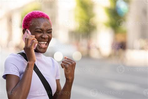 African Young Woman Laughing While Talking To The Mobile Outdoors