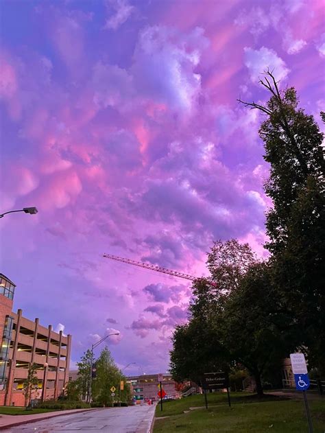 The Sky Is Pink And Purple As Clouds Are In The Distance With Buildings