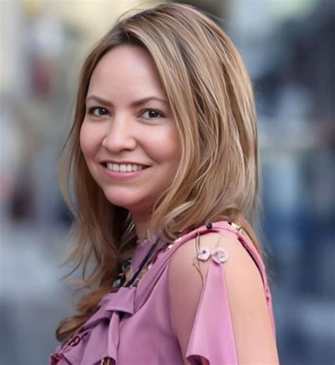 a woman in a pink top is smiling for the camera and she has blonde hair