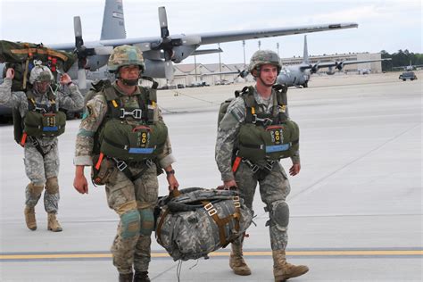 U.S. and British paratroopers carry gear to load onto a C-130 Hercules ...