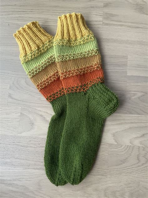 A Pair Of Knitted Mittens Sitting On Top Of A Wooden Floor