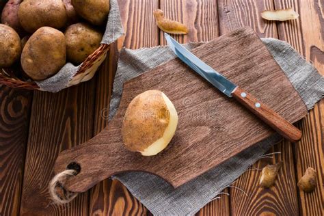 Unpeeled And Peeled Potatoes In A Basket And A Knife Stock Photo