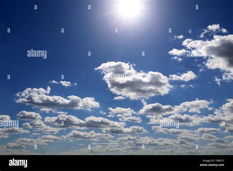 Shining sun and blue sky covered with white cumulus clouds. Summer ...