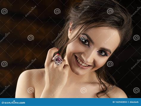 A Beautiful Smiling Brunette Girl With Bare Shoulders Joyfully Shows