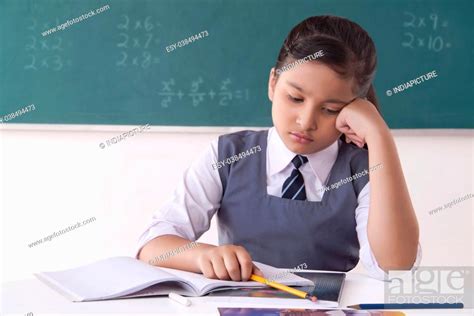 Girl Thinking While Writing Notes In A Classroom Stock Photo Picture