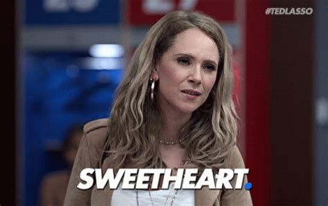 A Woman Standing In Front Of A Red Sign With The Words Sweet Heart On It