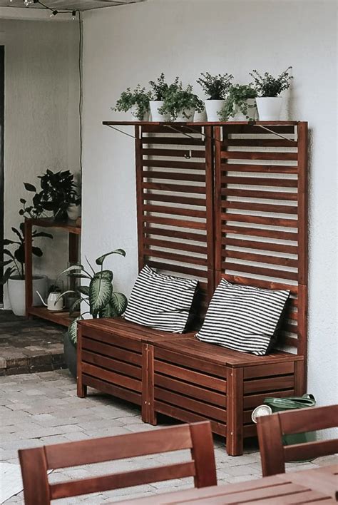 A Wooden Bench Sitting Next To A Wall With Potted Plants On Top Of It