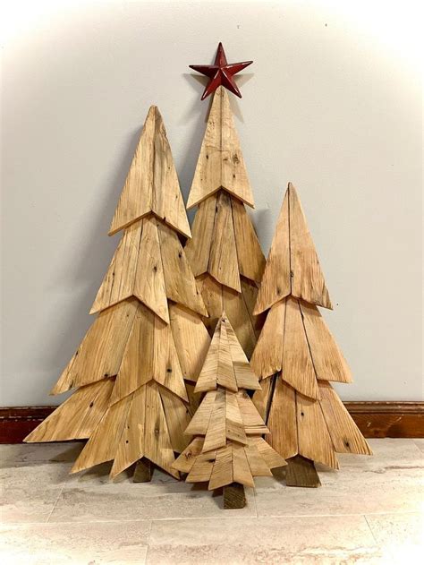 Three Wooden Christmas Trees Sitting Next To Each Other On The Floor In