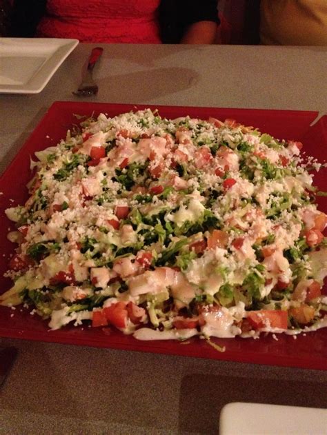 A Large Pizza Sitting On Top Of A Red Tray Covered In Cheese And Veggies