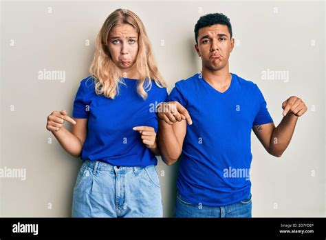 Young Interracial Couple Wearing Casual Clothes Pointing Down Looking