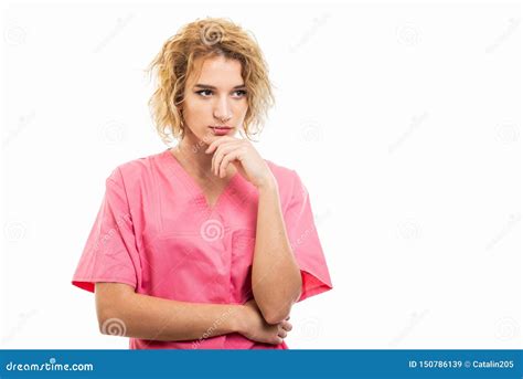 Portrait Of Young Nurse Wearing Pink Scrub Making Thinking Gesture