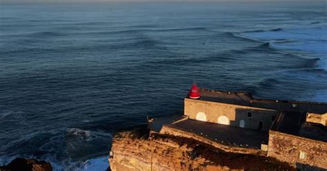 Sunrise Nazare Lighthouse with Large Waves crashing in the background ...