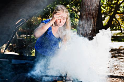 Panic Stricken Blonde Looks At Smoking Car Engine In Horror Stock Photo