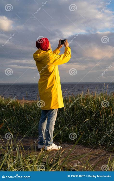 Man In Yellow Raincoat Wear Red Hat Standing On The Beach At Wooden