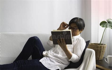 Old Smart Lady Wearing Glasses Reading Book For Relax Time At Living