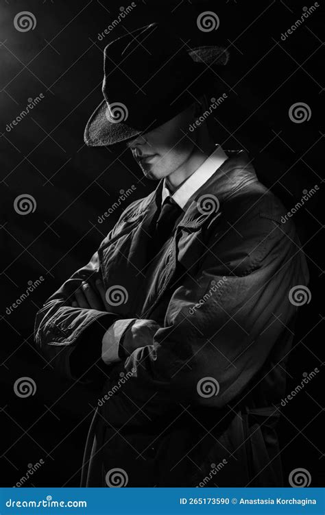 A Dark Silhouette Of A Man In A Raincoat And Hat With His Head Down In