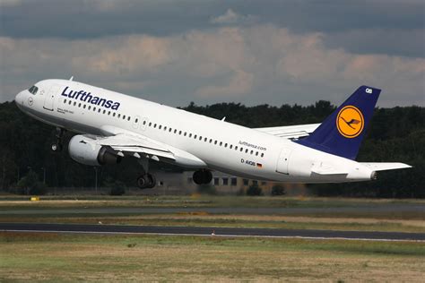 A Lufthansa Airplane Taking Off From An Airport Runway With Trees In