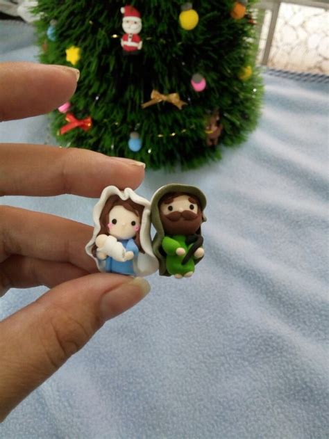 Someone Is Holding Two Small Figurines In Front Of A Christmas Tree