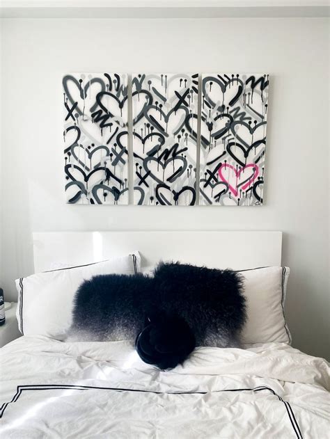 A White Bed Topped With Pillows Next To Two Paintings