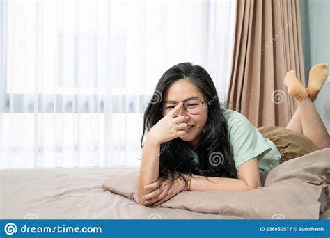 Beautiful Glasses Asian Woman Is Lying On Her Stomach And Looks At