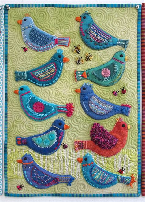 A Quilted Wall Hanging With Several Birds On It S Side And One Bird