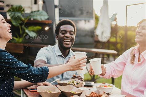 Happy people eating and cheering at food truck restaurant - focus the ...