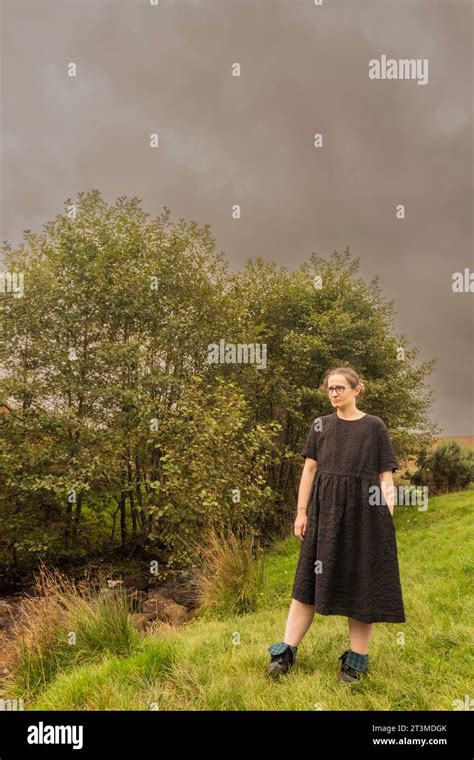 Solo Girl In Black Dress And Spectacles Standing By Some Bushes At Osmotherly North Yorkshire