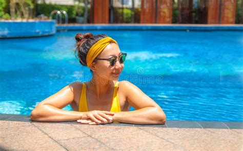 Beautiful Girl In A Yellow Swimsuit Resting In The Pool At The Hotel