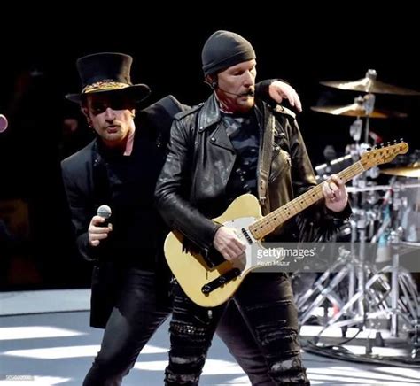 Two Men In Hats And Black Leather Outfits Are Playing Guitars On Stage