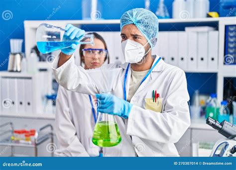 Man And Woman Scientists Pouring Liquid On Test Tube At Laboratory