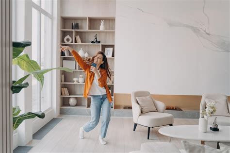 Mujer hispana feliz cantando en casa con teléfono móvil como con