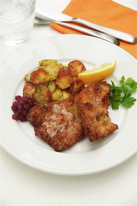 Wiener Schnitzel Breaded Veal Escalope From Vienna With Roast Potatoes Cranberries And Lemon