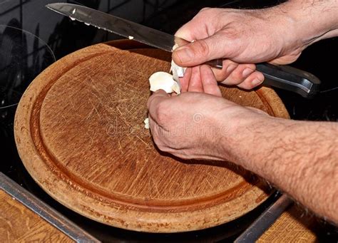 Cozinheiro Chefe Que Corta Alium Sativum Do Alho Na Placa De Corte