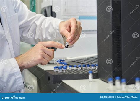 Scientist In Lab Coat Putting Vial With Sample Into Autosampler Of Hplc