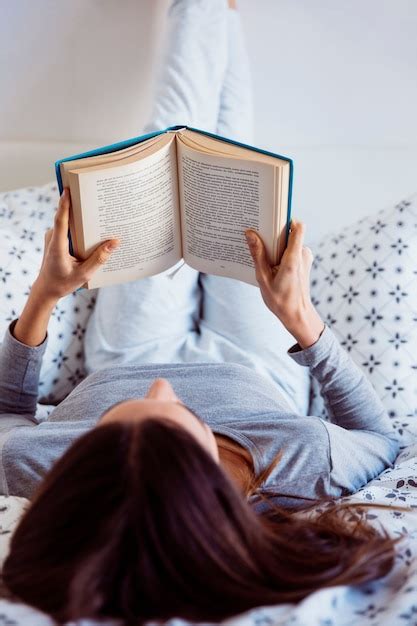 Mulher em pijama lendo na cama Foto Grátis