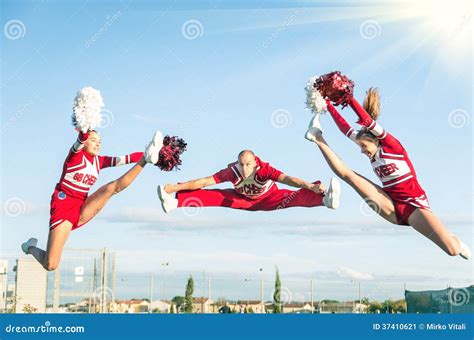 Cheerleaders Team Performing A Jump With Male Coach Stock Image Image