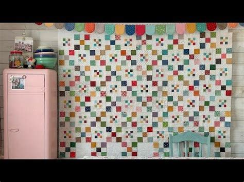 A Kitchen With A Pink Refrigerator And Colorful Quilt On The Wall