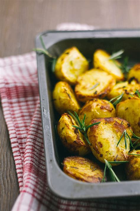 "Roast Potatoes With Rosemary In Roasting Tin" by Stocksy Contributor "Kirsty Begg" - Stocksy