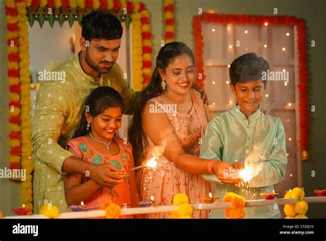 Happy parents with kids playing with diwali sparklers or Crackers by ...