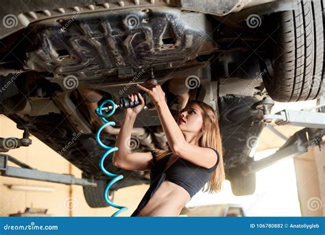 Pretty Woman Repairing Car With Pneumatic Key On Hydraulic Lift Stock