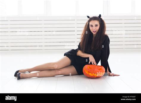 Smiling Brunette Woman In Halloween Makeup Posing With Carved Pumpkin