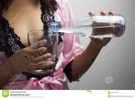 Manos Femeninas Que Vierten El Agua En Un Vidrio Foto De Archivo