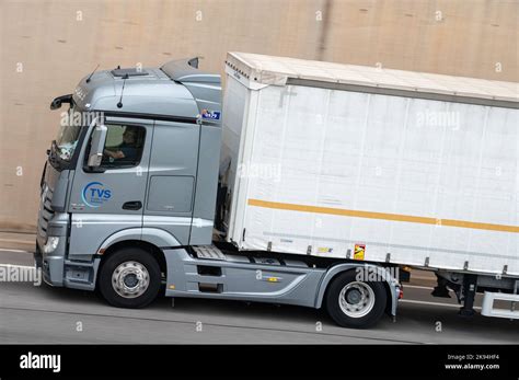 A Gray Mercedes Actros Truck Loading A White Container Trailer Along