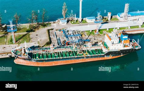 Aerial Shot Captures A Large Tanker Ship Moored At A Port Surrounded