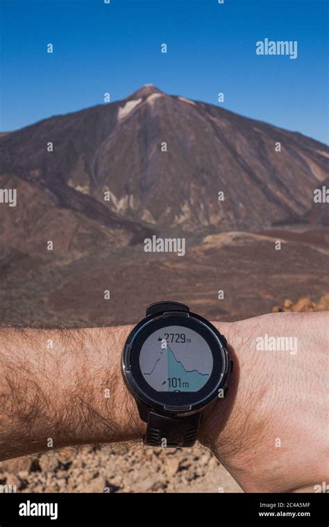 Runner checking progress on smart watch. Volcano on background Stock Photo - Alamy