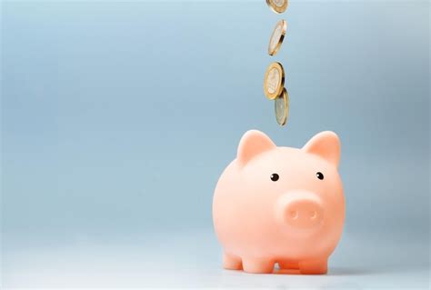 Premium Photo Pink Piggy Bank With Falling Coins On Blue Background