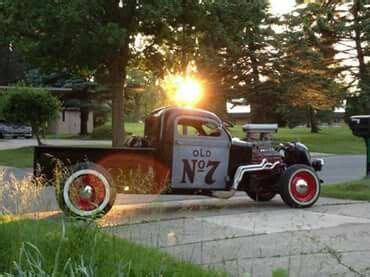 An Old Truck Parked On The Side Of The Road Near Some Grass And Trees