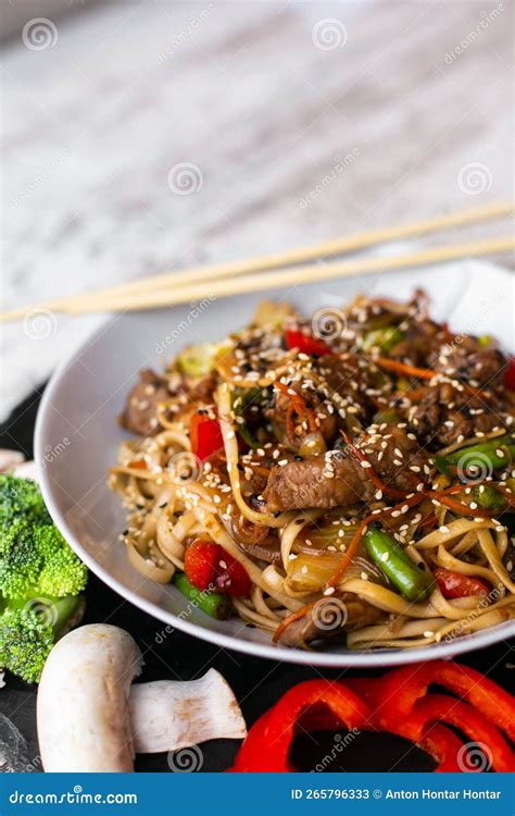 Wok Noodles Veal Udon On Black Plate And A Wooden White Background