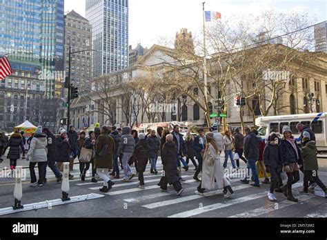 Pedestrians Cross 42nd Street Along 5th Avenue With The New York Public